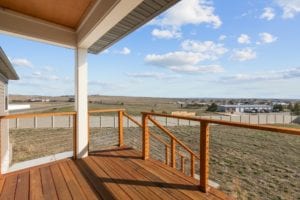 Covered patio with distinctive wood railing in a new home construction of a single family home in Billings MT, a Safe and Secure kid friendly neighborhood.